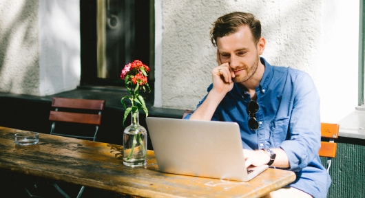 young-man-using-laptop-while-sitting-by-table